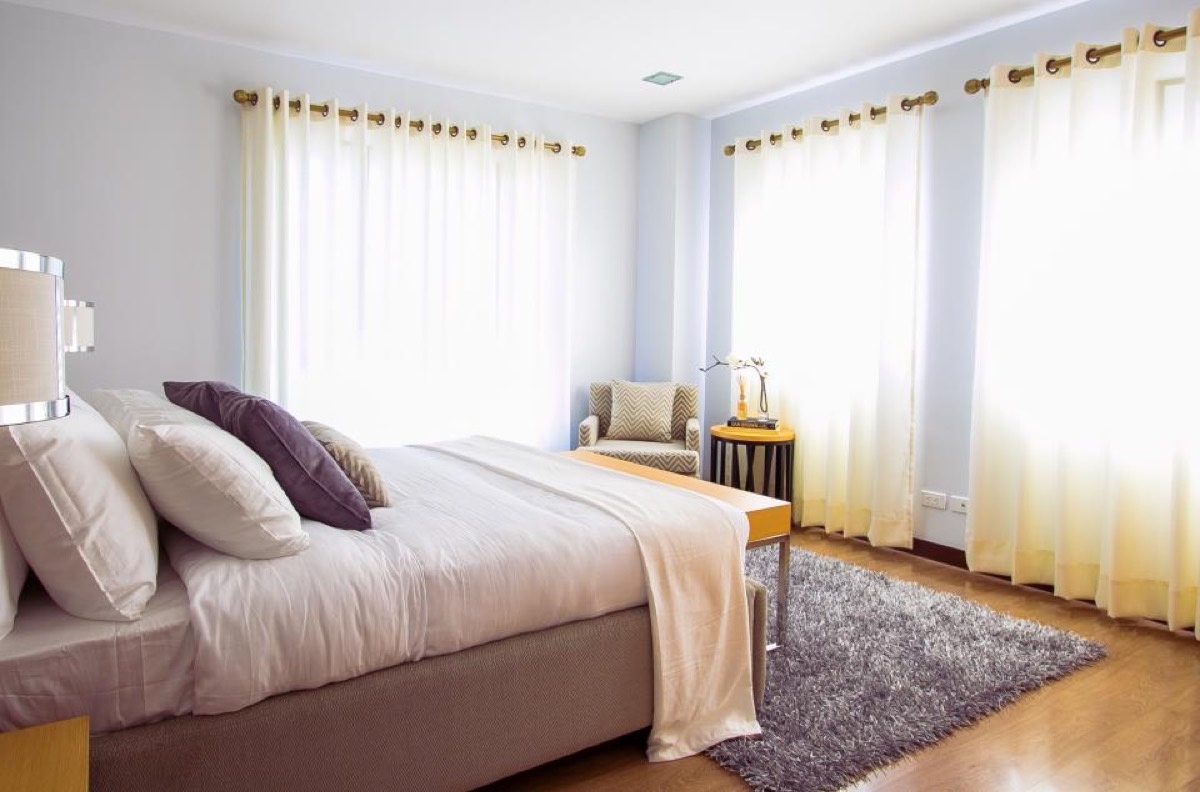 Bright bedroom with hardwood floors and soft curtains